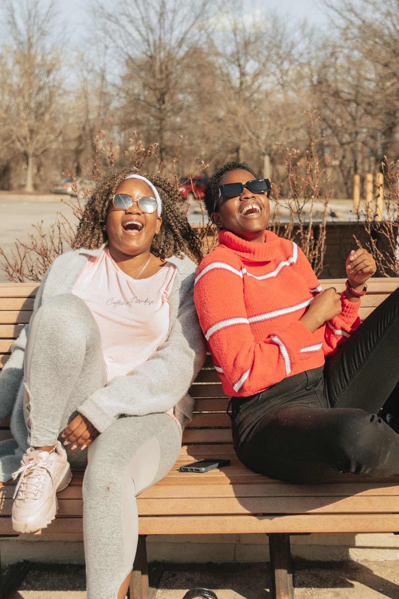 Two Black women laughing together on a bench